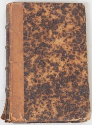 un vieux livre à la couverture brune posé sur une surface blanche
