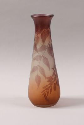a brown vase with leaves on it sitting on a table
