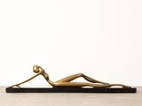 a bronze statue of a woman laying down on a black base