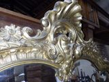 a gold mirror in a room with a wooden wall behind it