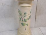 un vase blanc orné de feuilles vertes, posé sur une table