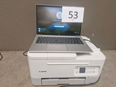 a laptop sitting on top of a printer on a table