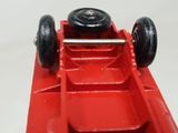 a red toy car with black wheels on a white surface