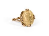 un gros plan d'une bague en forme de pièce d'or sur fond blanc