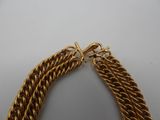a close up of a gold chain bracelet on a white surface