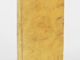 un vieux livre à la couverture jaune posé sur une surface blanche