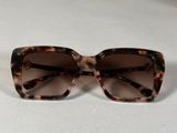des lunettes de soleil de couleur marron tortue posées sur une surface blanche