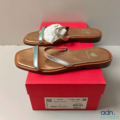 une paire de sandales pour femme dans une boîte posée sur une surface blanche