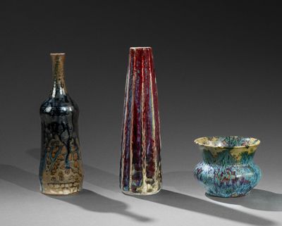 trois vases en verre de couleurs différentes posés les uns à côté des autres sur une table