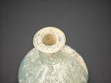 a green glass vase sitting on a black surface