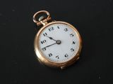 a gold pocket watch with a white face on a black surface
