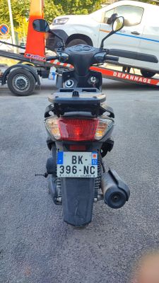 a motorcycle that is parked on the street with a tow truck in the background