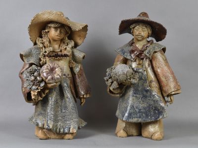 two figurines of two people with hats and holding flowers