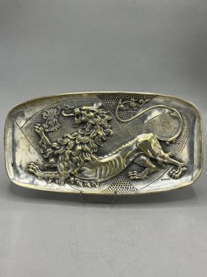 a silver plate with a lion and flowers on it