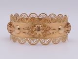 a close up of a gold bracelet on a white surface