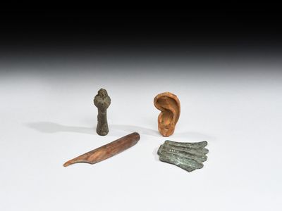 trois morceaux de métal et un objet en bois posés sur une surface blanche