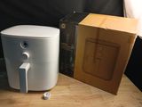 a white air fryer sitting on a table next to a box