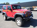 a red jeep parked in a parking lot with other cars in the background