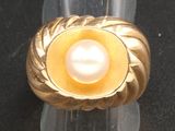 bague en perles jaunes et blanches posée sur un socle en acrylique transparent