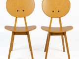 two wooden chairs with faces on the back of them