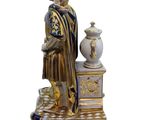 a figurine of a man sitting on a table with a vase