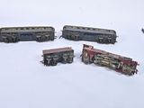 four toy trains sitting on a white surface next to a pair of scissors