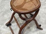 an old wooden stool with a wicker seat sitting on a cement floor
