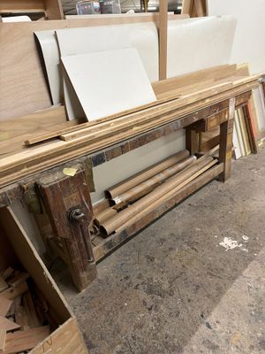 Plusieurs morceaux de bois sont empilés sur un établi dans un atelier