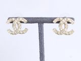 une paire de boucles d'oreilles Chanel posée sur un présentoir