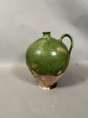 un vase vert posé sur une table, sur fond blanc