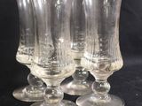 four clear wine glasses sitting on top of a black table