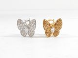 une paire de boucles d'oreilles en forme de papillon, dorées et argentées, sur fond blanc