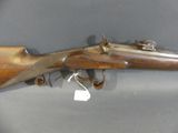 an antique rifle with a wooden barrel and brass fittings on display