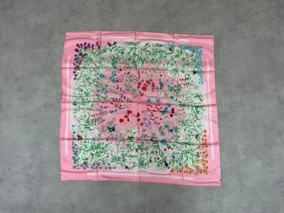 un foulard carré à motifs floraux roses et verts accroché à un mur
