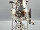 an antique silver plated coffee urn with a bird on it