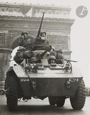 an old photo of a military vehicle driving down the street