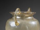 a glass vase with a gold handle on a table