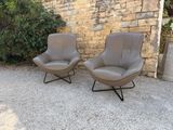 two chairs sitting next to each other in front of a stone wall