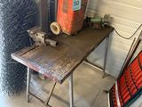 une petite table sur laquelle est posée une soudeuse, dans un garage