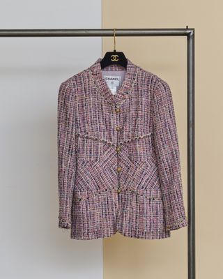 une veste rose suspendue à un portant près d'un mur blanc