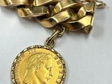 a close up of a gold chain bracelet with a coin on it