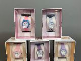 trois boîtes contenant chacune quatre montres différentes, posées sur une table