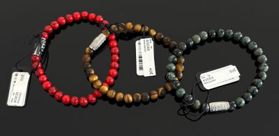 trois bracelets de couleurs différentes, munis d'étiquettes, posés sur une surface noire