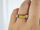someone is holding a ring with a yellow stone in it