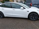 a white tesla model 3 parked in a parking lot