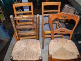 quatre chaises en bois disposées les unes à côté des autres sur un tapis