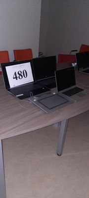 deux ordinateurs portables posés sur une table dans une pièce équipée de chaises orange