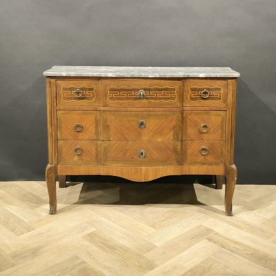 an antique chest of drawers with marble top on a wooden floor