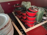 de nombreuses casseroles et poêles rouges et vertes sur une étagère