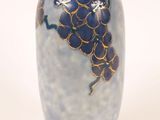 un vase bleu orné d'une grappe de raisin